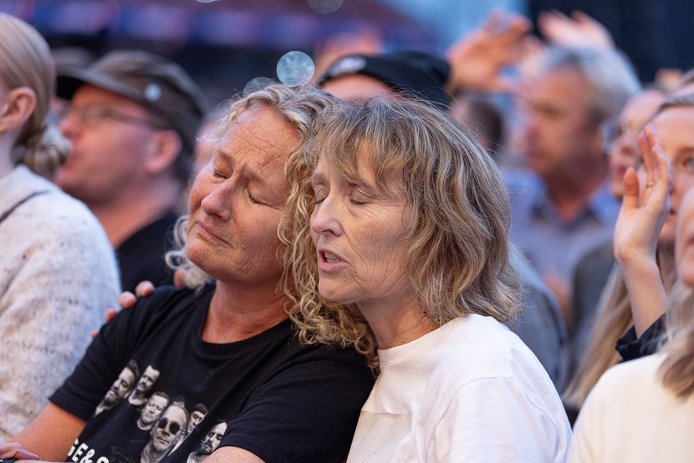 To damer står i publikum med øynene lukket og lener hodene mot hverandre. Tydelig rørt, begge to